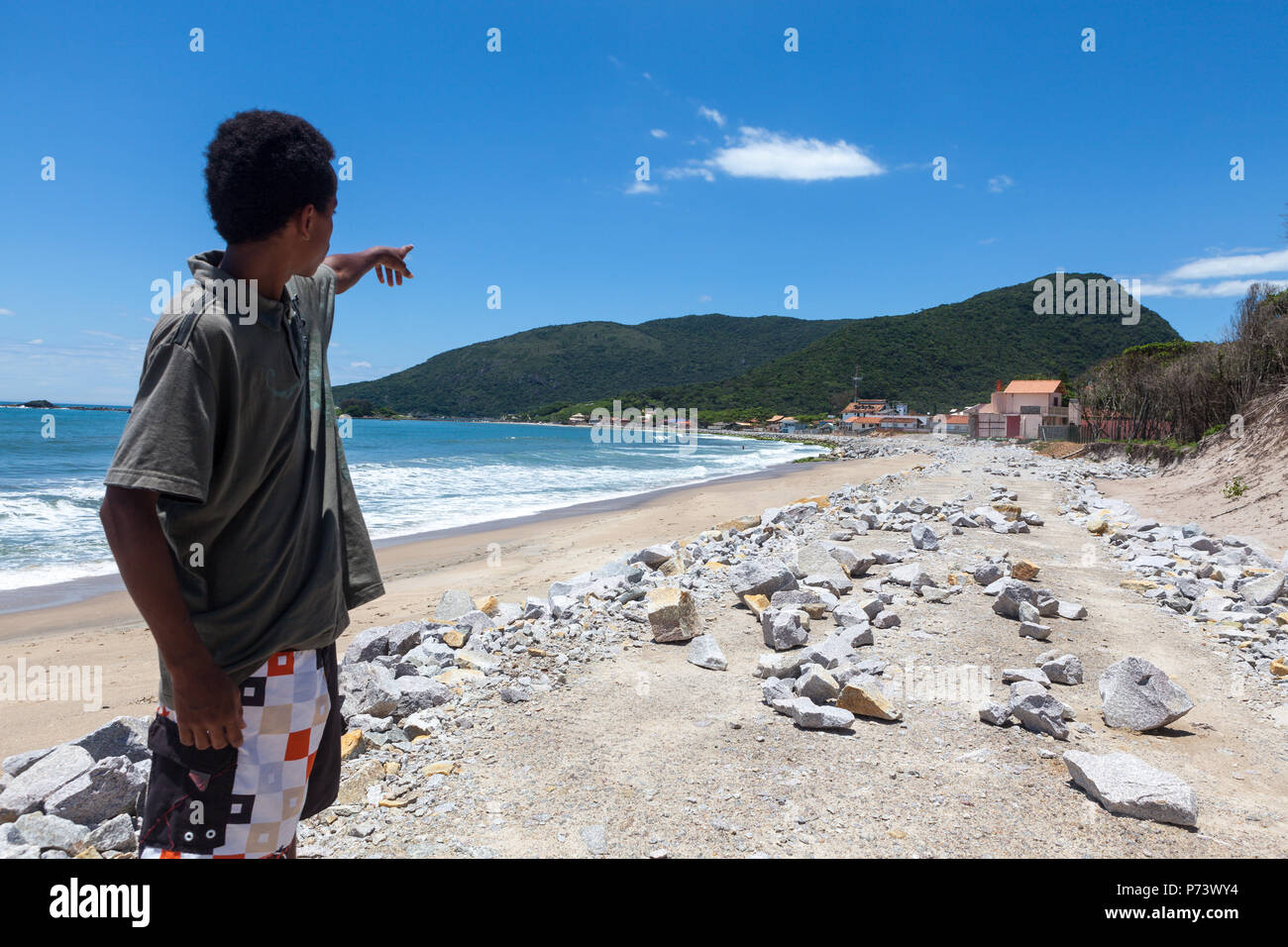 Florianopolis, Santa Catarina, Brasilien. Junge an der Straße von Wellen im Meer zerstört auf der Suche beim Strand. Auswirkungen des steigenden Meeresspiegels. Stockfoto