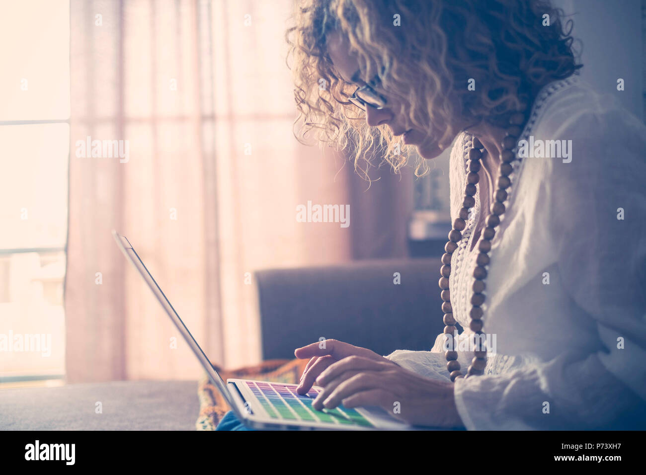 Schöne konzentrierte kaukasische Frau mittleren Alters Arbeiten am Laptop mit farbigen Suchbegriffe. Schriftsteller Arbeit zu Hause für alternativen Lebensstil und offic Stockfoto