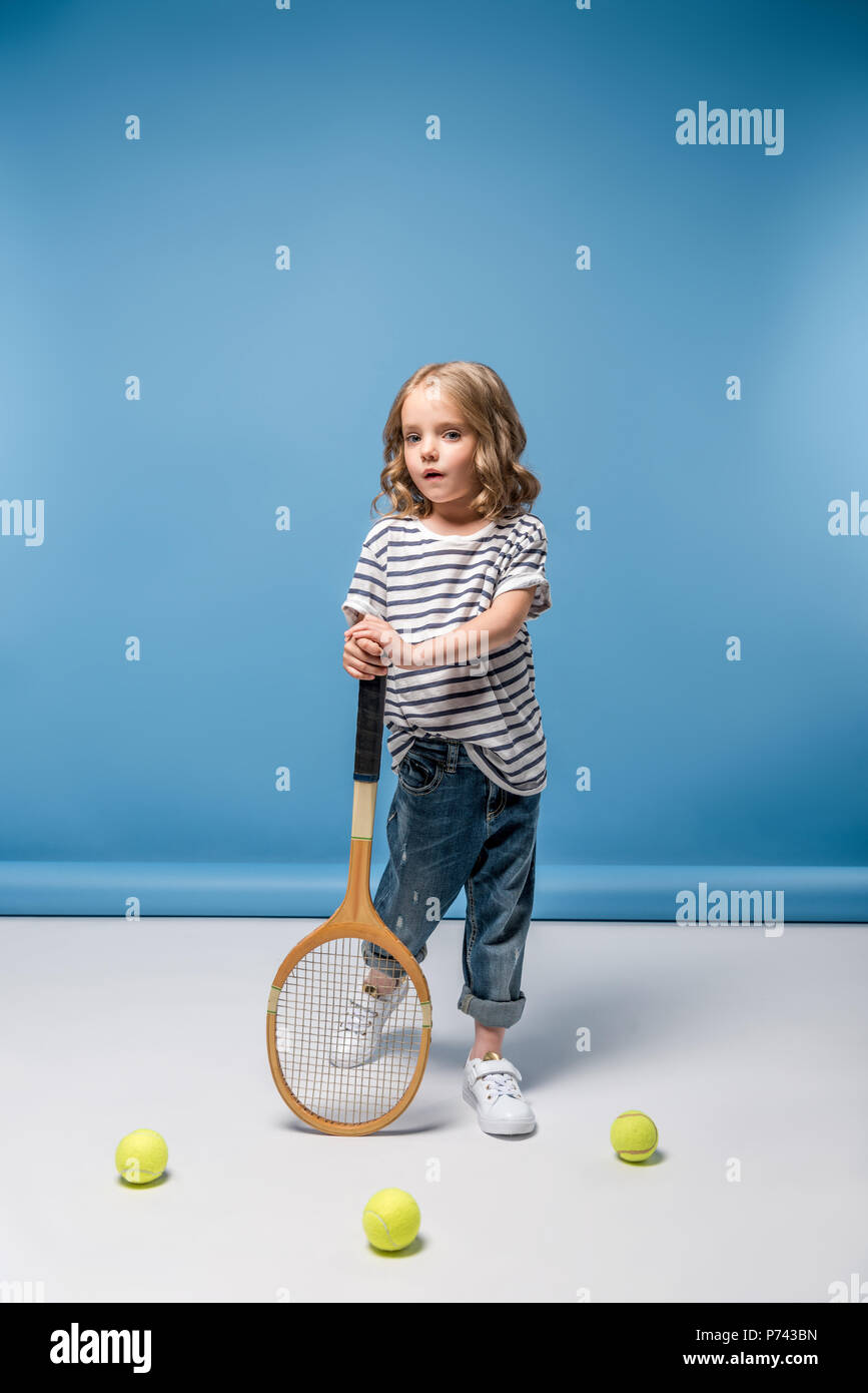 Kleines Mädchen mit Tennis raquet und Kugeln auf Blau Stockfoto