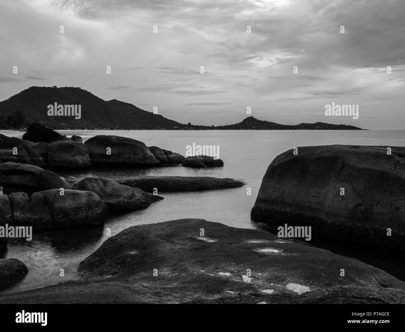 Großen Felsen in der Nähe von Meer mit dem fernen Land. Schwarz und Weiß Stockfoto