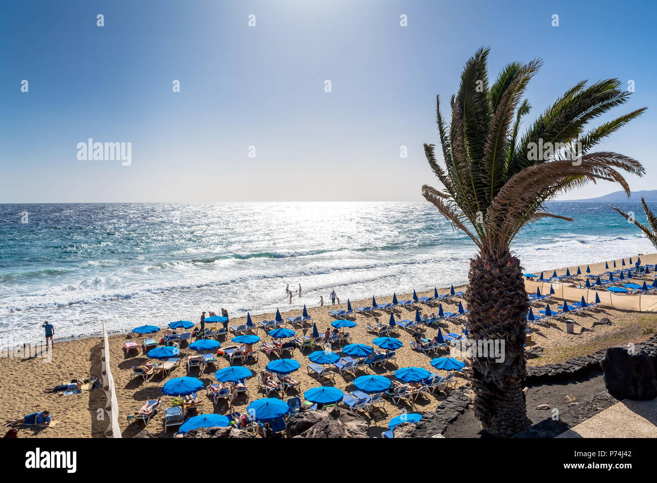 Puerto del Carmen, Spanien - 29. Dezember 2016: Tag der Blick auf den Strand mit Palmen und Touristen in Puerto del Carmen, Spanien. Puerto del Carmen ist der Main Tour Stockfoto