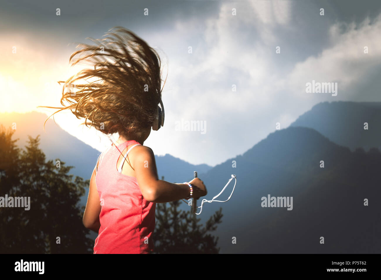 Kleines Mädchen mit ihrem Haar im Wind hört Musik mit Player und Kopfhörer. Stockfoto