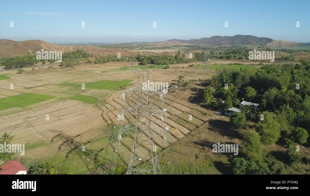 Strommasten und hohe Spannung, die durch die Berge der Cordillera. Philippinen, Luzon. Luftaufnahme von Hochspannung Metall post, Turm. Elektrische Stromleitungen über Bäume. Stockfoto