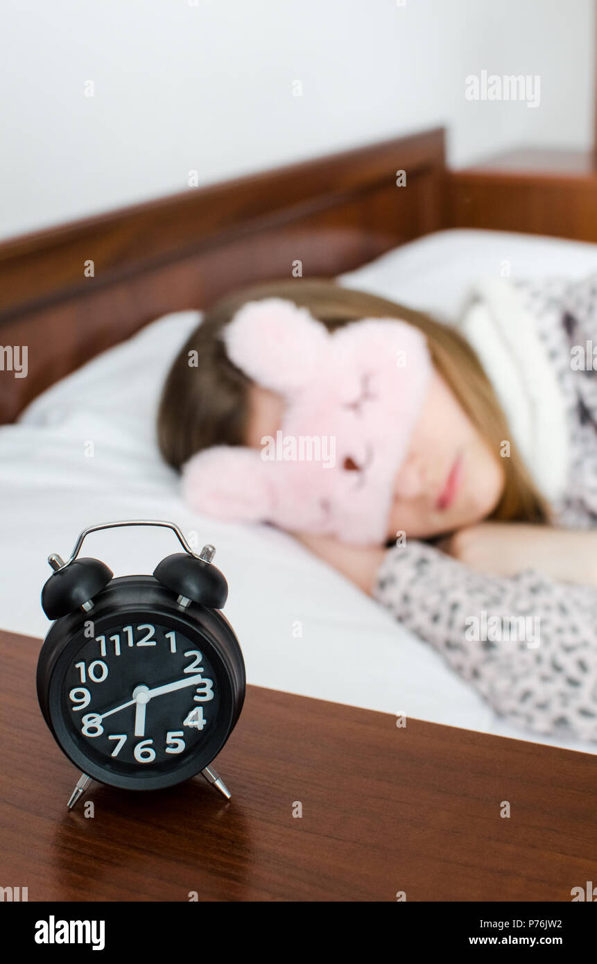 Junge Frau Mädchen in süßen Schlaf Maske und warme Schlafanzüge schlafen  mit Wecker am Bett am Morgen. Schlafende Mädchen und Radiowecker im  Schlafzimmer. Jugendlich Stockfotografie - Alamy