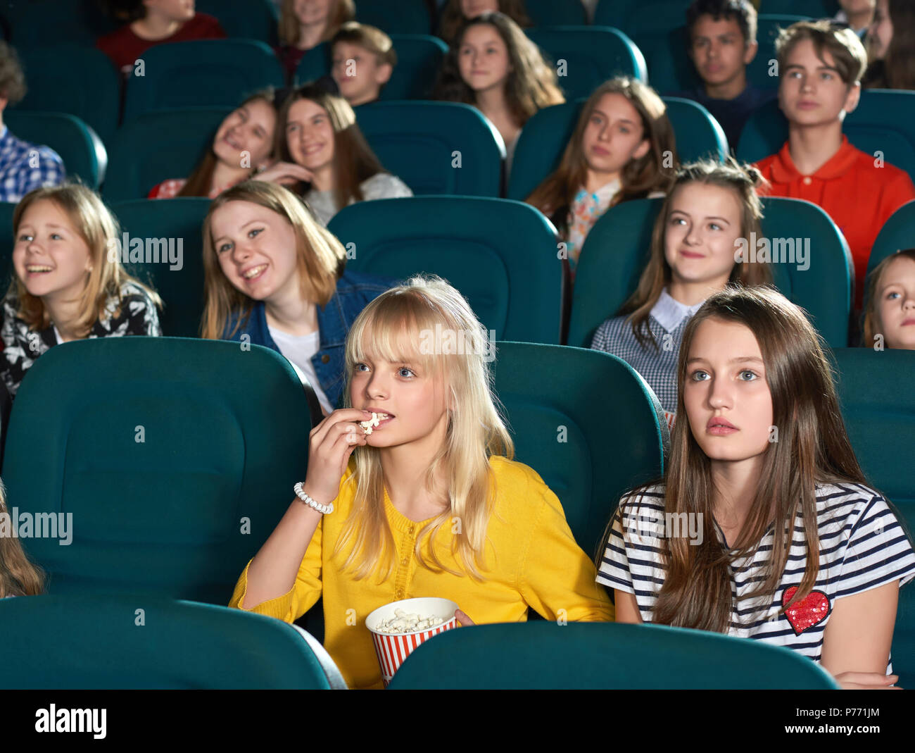 Schöne Mädchen auf der Suche nach Bildschirm mit unerschütterlichem Augen und beobachten interessanter Film. Süße blonde Essen Popcorn, kleines Mädchen trinken Kohlensäure trinken. Sp Stockfoto