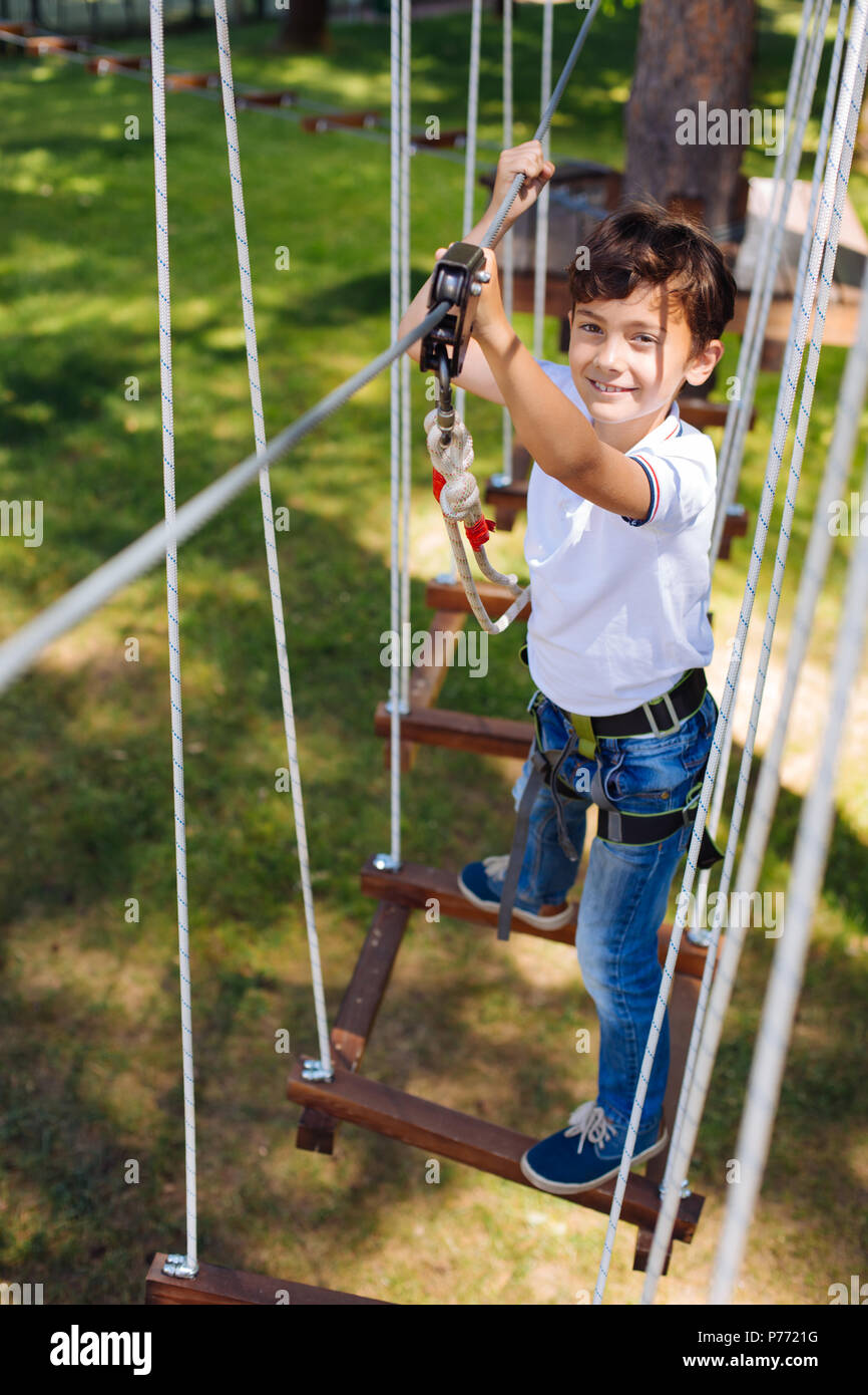 Blick von oben auf die fröhliche Jugendliche junge Klettern im Seilpark Stockfoto