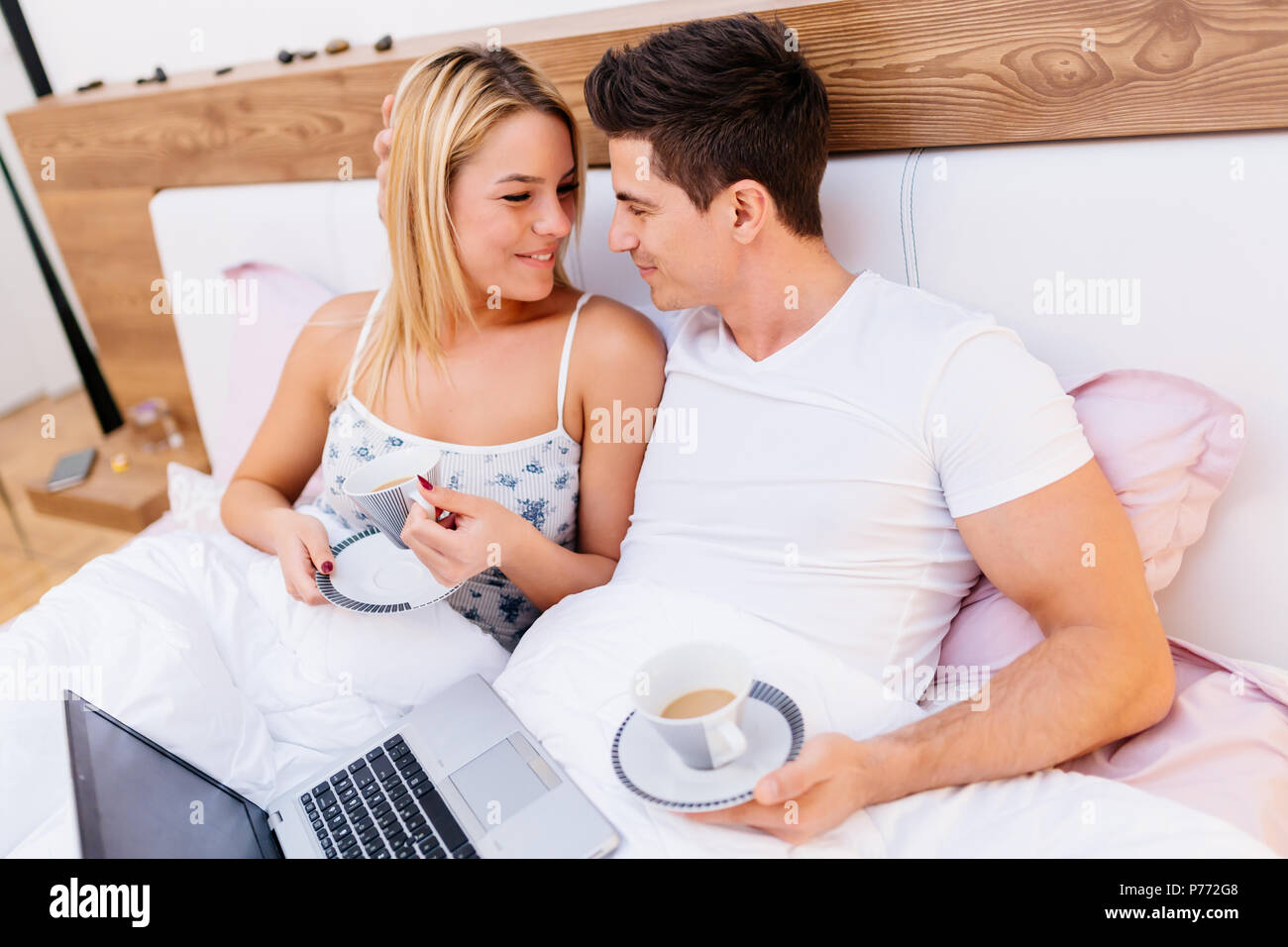 Verliebtes Paar holding Kaffee, während im Bett Stockfoto