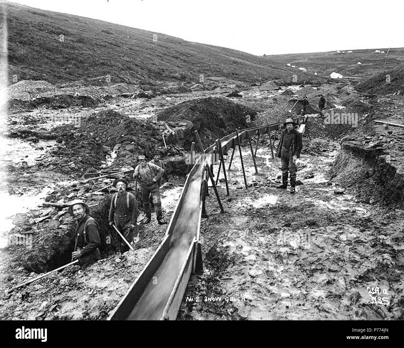 . Englisch: Bergbau Behauptung Nr. 2 am Schnee Gulch, Alaska, Ca. 1901. Englisch: Wahrscheinlich Schnee Gulch gelegen 6 Meilen nördlich von Nome auf dem Seward Peninsula. Zeigt Bergleute mit dem Sanitärsystem. Der Mann auf der rechten Seite, vor und durch selbst ist Johan Olsen Sjolseth (1867 - 1938) von Oksendal in Norwegen. Nach 10 Jahren in Alaska, ging er in Schnittholz in Hoquiam, und wurde dann ein Landwirt auf Tanne Insel. (Anmerkung von Jan O. Kolmann Johnsen. 07/2009) Bildunterschrift auf Bild: "Nein. 2 Schnee Gulch" Bild im Hegg Album 28, Seite 37. Original Foto von Eric A. Hegg 1821; von Webster und St kopiert Stockfoto