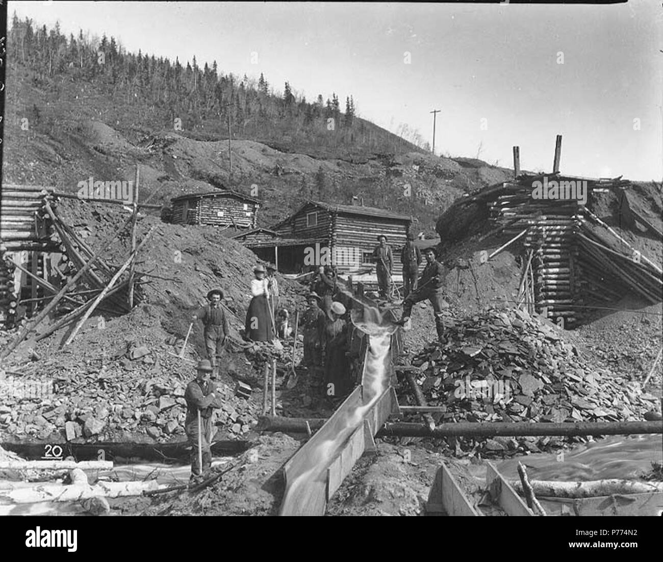 . Englisch: Bergbau Betrieb mit Schleusen, Unbekannter Ort, vermutlich Yukon Territory, Ca. 1898. Englisch: Zeigt zwei Frauen und acht Männer mit Kabine im Hintergrund. Nr. 20 erscheint in der unteren linken Ecke des Bildes. Klondike Gold Rush. Themen (LCTGM): Gold Miner - Yukon; Gold mining -- Yukon; Bergbau Ansprüche -- Yukon; Schleusen - Yukon; Frauen - Yukon; Log Bauten - - Yukon Themen (LCSH): Yukon - Gold Entdeckungen. ca. 1898 9 Bergbau Betrieb mit Schleusen, Unbekannter Ort, vermutlich Yukon Territory, ca 1898 HEGG (549) Stockfoto
