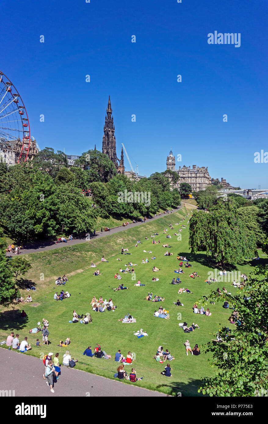 Die Menschen genießen die Sonne im Osten die Princes Street Gardens mit dem Scott Monument und der Balmoral Hotel Edinburgh Schottland Großbritannien Stockfoto