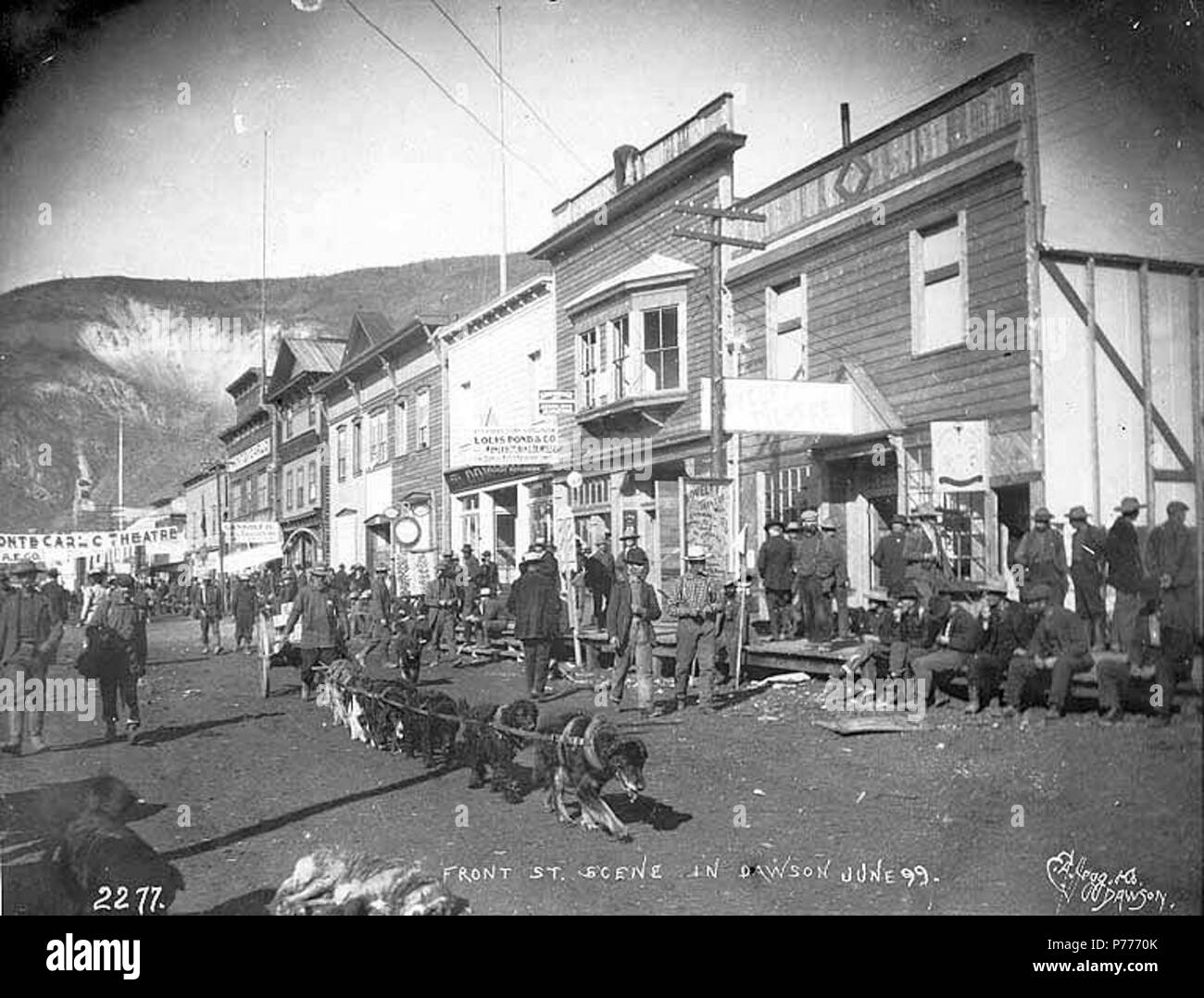 . Englisch: Front St., Dawson City, Yukon Territory, Juni 1898. Englisch: Zeigt dogteam schleppen Warenkorb in Street, 'Louis Teich & Co.' und 'Monte Carlo Theater' auf der rechten Seite auf das Bild Bildunterschrift: "Front St. Szene in Dawson Juni '99.''. Klondike Gold Rush. Themen (LCTGM): Straßen---- Yukon Dawson; Werbung ------ Yukon Dawson; Hund Mannschaften - Yukon - Dawson; Karren & Wagen ------ Yukon Dawson; Geschäfts----- Yukon Dawson; Theater ------ Yukon Dawson Themen (LCSH): vordere Straße (Dawson City, Yukon); Louis Teich & Co (Dawson City, Yukon); Monte Carlo Theater (Dawson City, Yukon). 1898 5 Front St, Dawson City, Yukon Territory, Juni 1898 ( Stockfoto
