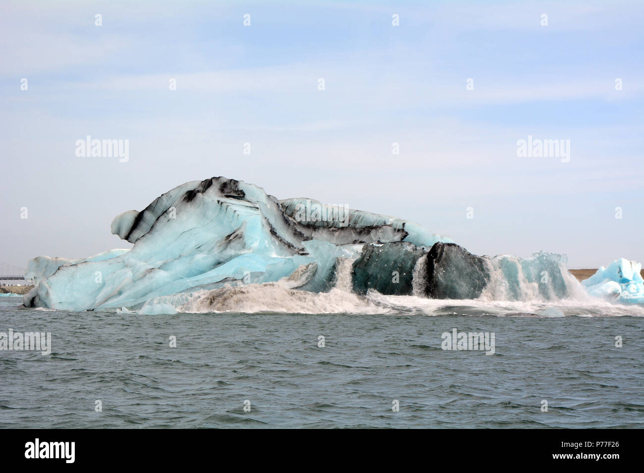 Eisberg im Isländischen Gletscherlagune umklappen, nachdem ein Stück abgebrochen Stockfoto