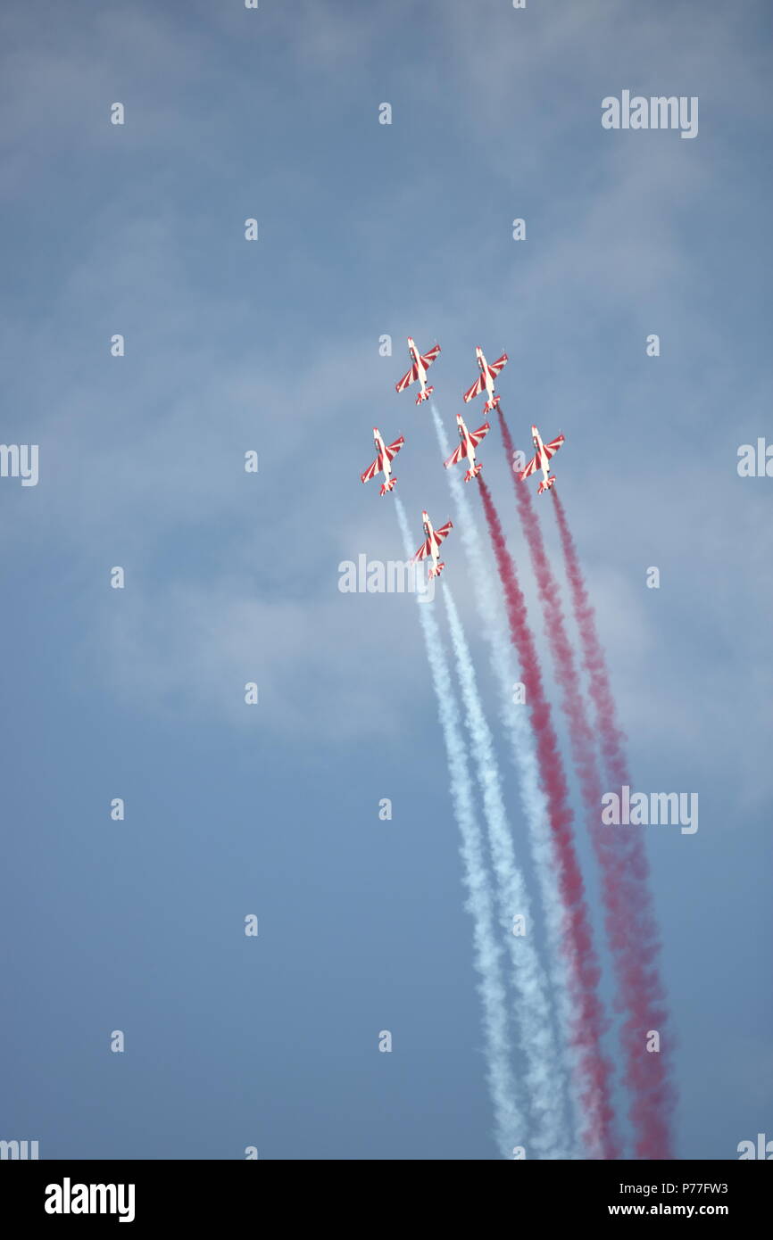 Sechs sport Flugzeuge tun gefährliche Kunstflug in der Luft, fliegen nahe beieinander, Vertikal, weißen und roten Rauch in der Luft verlassen Stockfoto