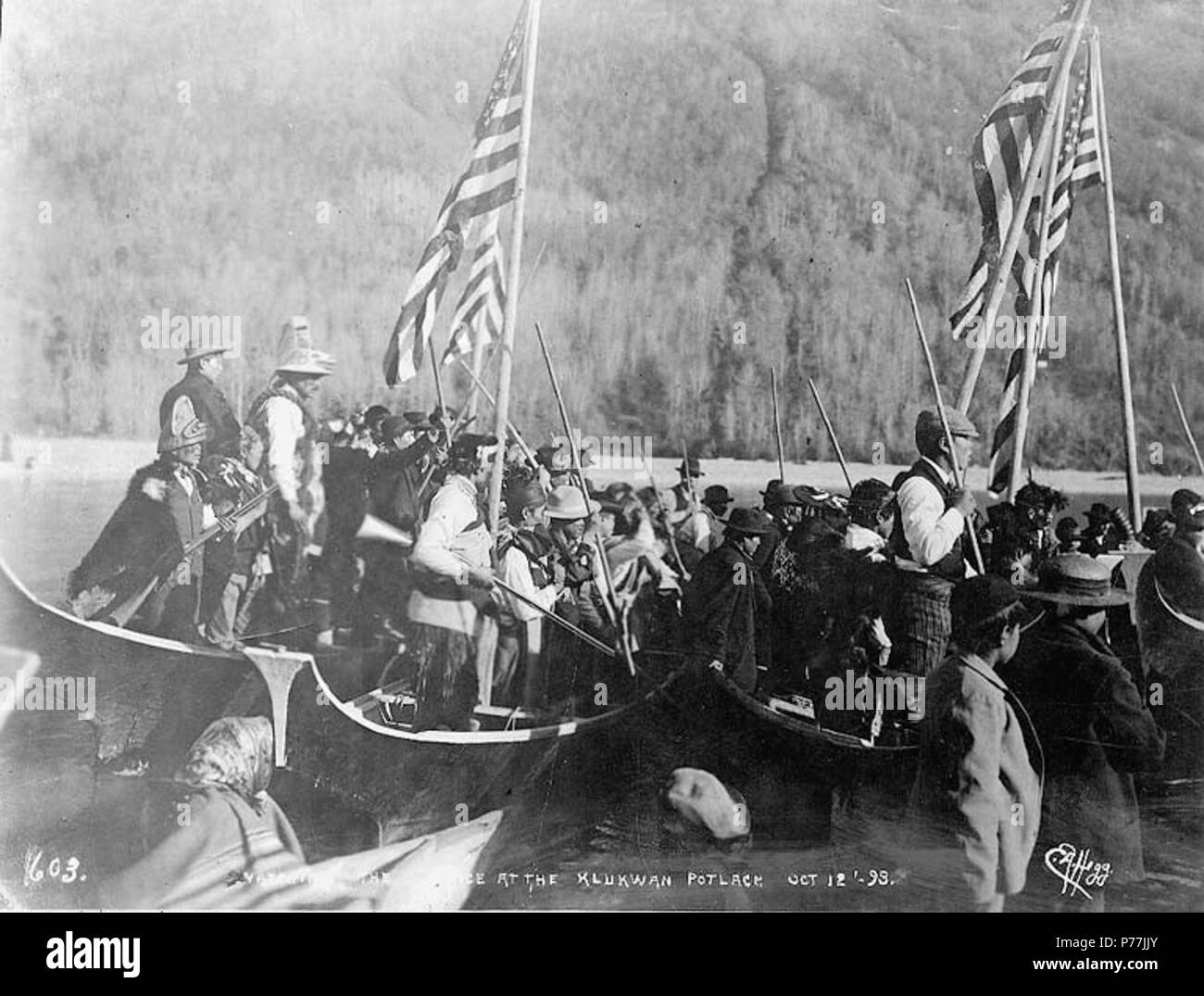 . Englisch: Zuschauer in Kanus auf der Tlingit Potlatch, Klukwan, Alaska, 12. Oktober 1898. Englisch: Zeigt Tlingit Indianer in den zeremoniellen und westlicher Kleidung, einige Holding Gewehre und die amerikanische Flaggen. Bildunterschrift auf das Bild: "Gerade die Tanz an der Klukwan potlach Okt 12'98'' Themen (LCTGM): Kanus - Alaska - klukwan Themen (LCSH): Tlingit Indianer - Alaska - klukwan; Potlatch - Alaska - klukwan; Indianer Nordamerikas - Soziales Leben und Brauchtum. 1898 12 Zuschauer in Kanus auf der Tlingit Potlatch, Klukwan, Alaska, 12. Oktober 1898 (HEGG 472) Stockfoto