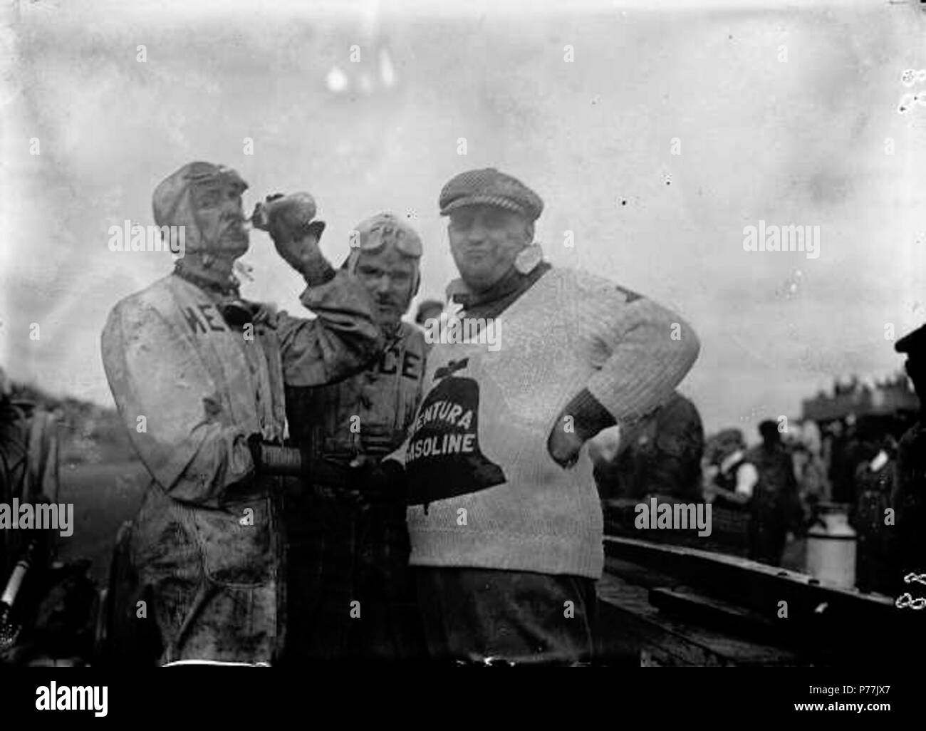 Englisch: Vincent E. 'Ventura' McDermott, das Tragen eines schweren Pullover mit Benzin 'Ventura' Emblem prangt, schüttelt Hände mit einem Rennfahrer aus einem Glas trinkt, Flasche in diesem ca. noch 1915 an der Tacoma Speedway genommen. Herr McDermott hatte nach Tacoma für die großen Juli auto Klassiker kommen, unter Umgehung der Anschläge in Chicago und Omaha. Die Ventura Marke von Gas war beliebt bei Racers als Autos mit kam in der Ersten, Zweiten und fünf weitere Orte im Juni, 1915, Indianapolis 500, accummulating $ Zwar dürfte in den Preisen. Die beiden anderen Racers in der Fotografie waren nicht positiv, obwohl die ma identifiziert Stockfoto