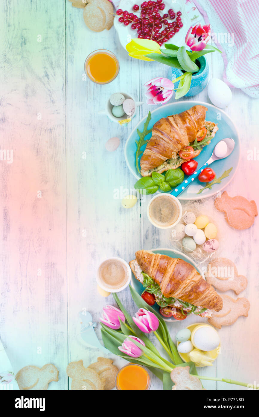 Osterfrühstück. Eine Familie Frühstück mit Croissants mit Rucola und Käse und aromatischen Kaffee. Frische Tulpen rosa Farbe und Eier in verschiedenen Farben und Ostern Dekor. Freier Platz für Text Stockfoto