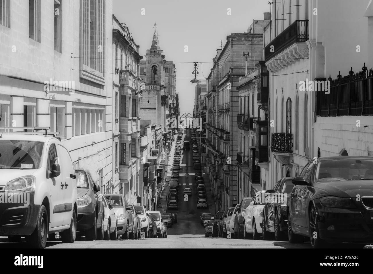 Eine lange gerade Straße in Valletta, Malta in Schwarz und Weiß mit einem riesigen Linie der Autos entlang der Straße geparkt werden. Stockfoto