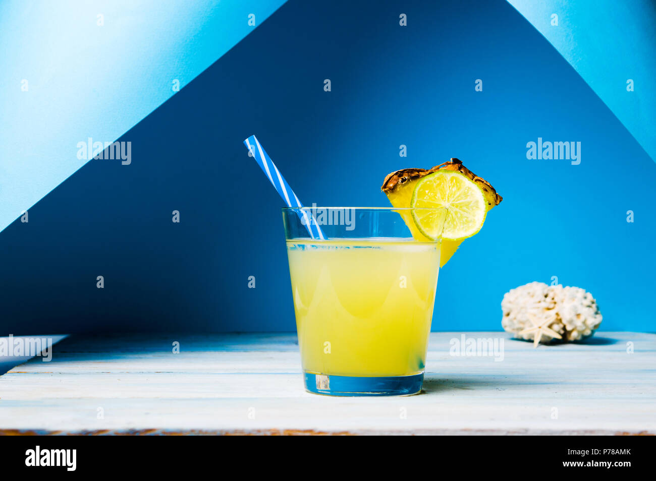 Ananas Saft in ein Glas mit Obst gegen den blauen Hintergrund Stockfoto