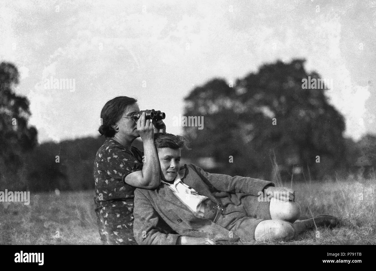 1930er Jahre, historische Bild eines Schülers mit seiner Mutter, die mit dem Fernglas etwas in der Ferne, England, UK zu sehen. Stockfoto