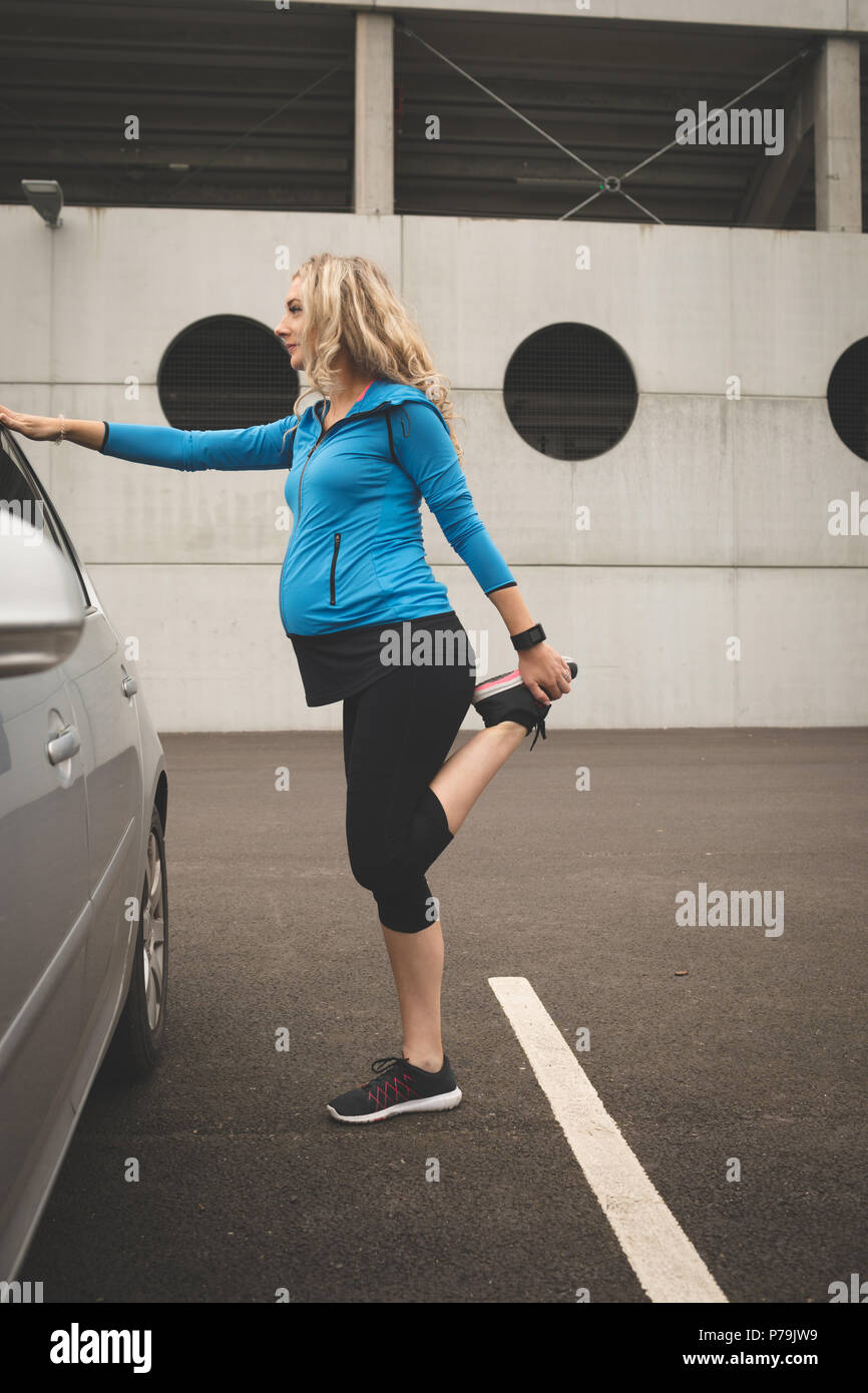 Schwangere Frau Ausübung auf einem Auto Stockfoto