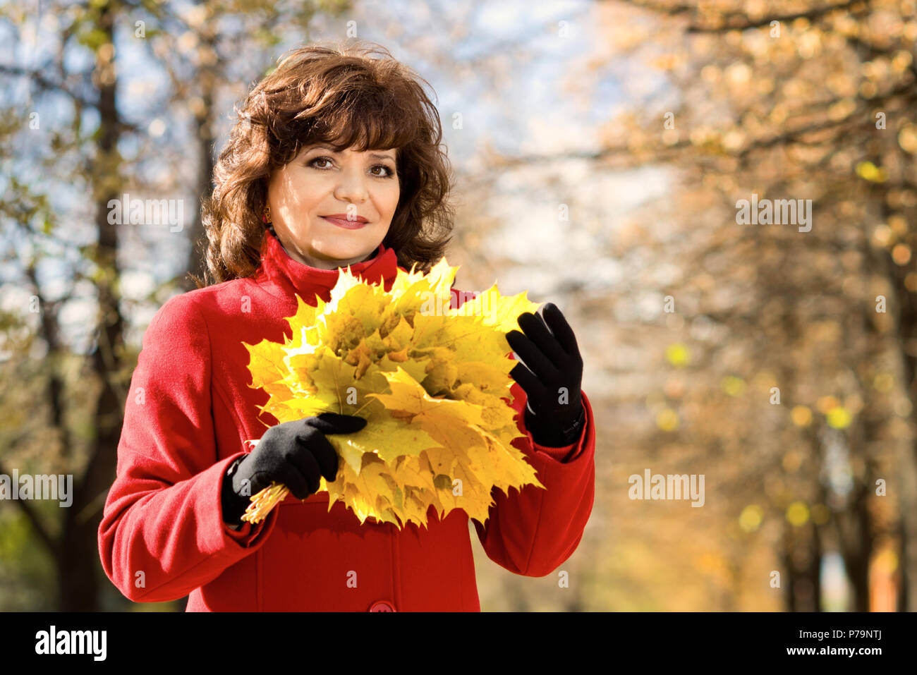 Die Reife schöne Frau im roten Mantel, outdoor im Park, Herbsttag Stockfoto