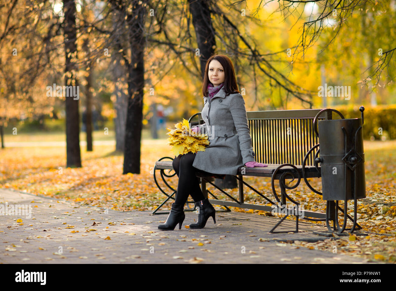 Horizontale Foto, schöne Mädchen sitzen auf der Bank im herbstlichen Park Stockfoto