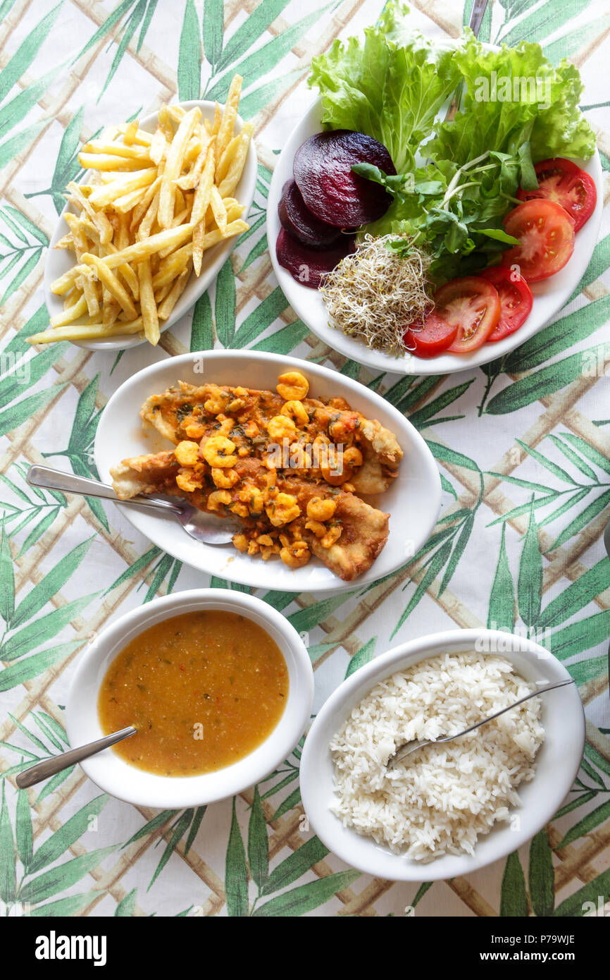 Florianopolis, Santa Catarina, Brasilien. Gerichte der typischen Strand Essen: gebratene Garnelen, Reis, Salat, Pommes und Fischeintopf auf einem rustikalen Tisch serviert mit Whi Stockfoto