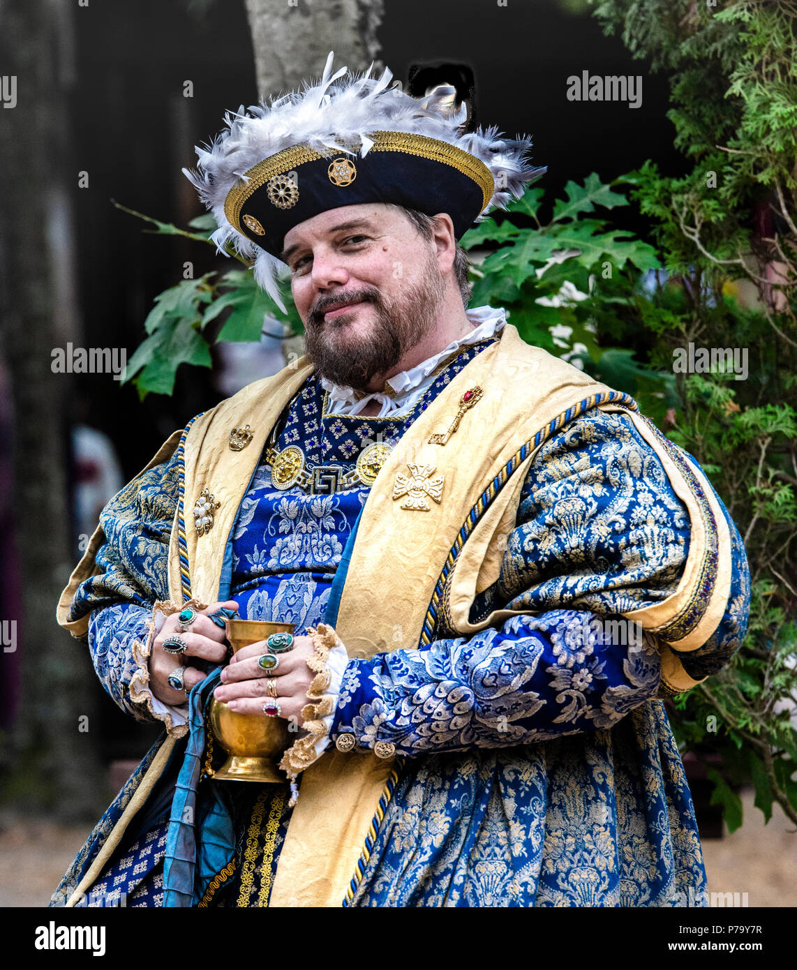 Maryland Renaissance Festival Schauspieler porträtiert König Henry VIII ruht im Freien, bei einem Drink in seinem bejeweled Hände. Er lächelnd vor der Kamera. Stockfoto