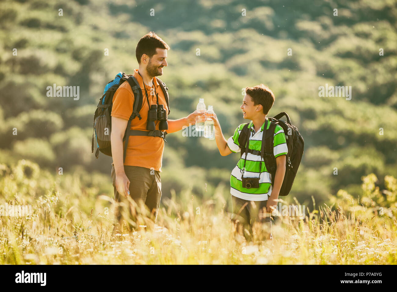 Vater und Sohn sind das Wandern in der Natur im Sommer. Sie sind Trinkwasser. Stockfoto