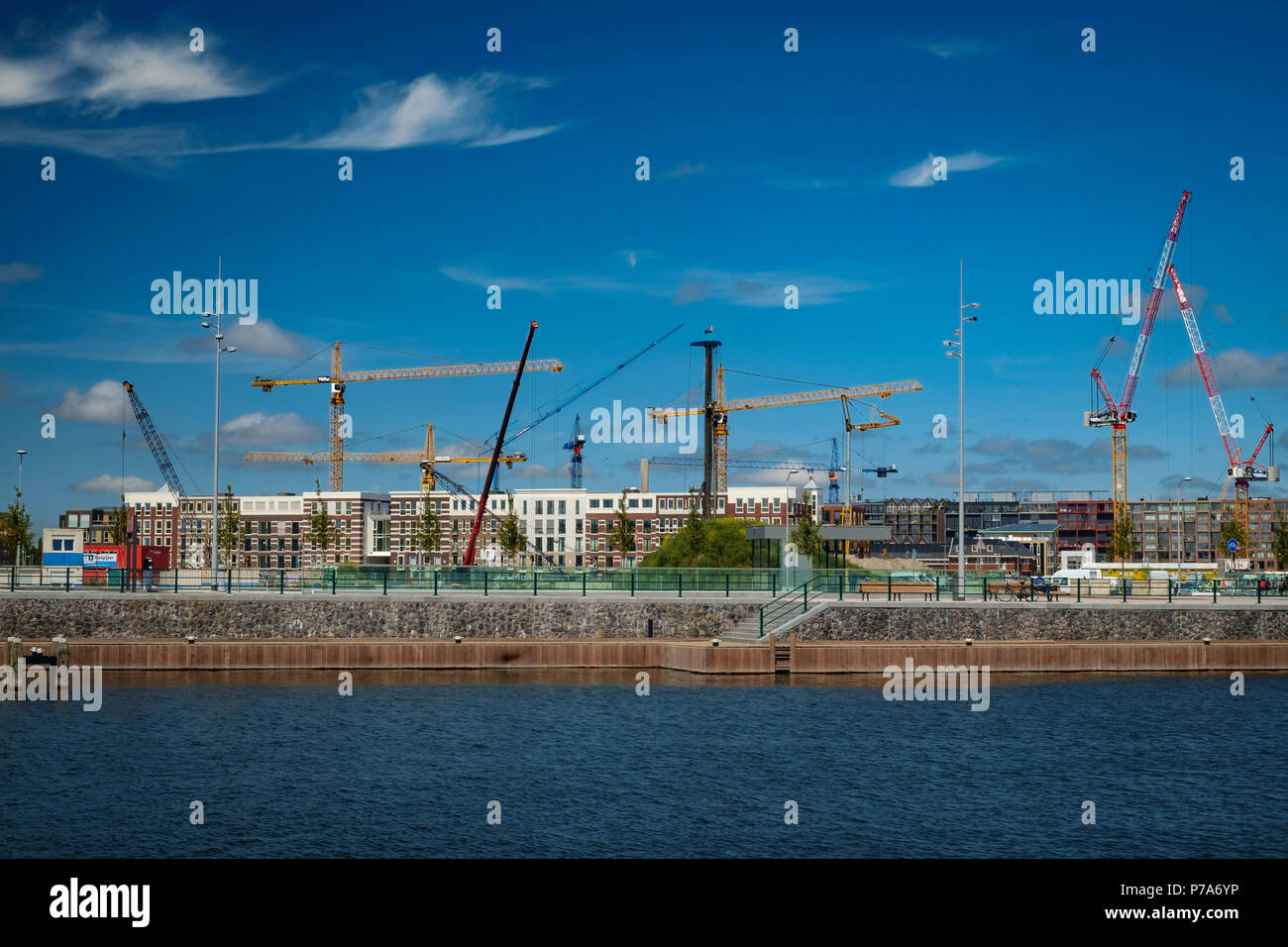 Eine wir-Krieg von hohen Kräne Aufstieg über eine neue Wohnanlage in den alten Hafen von Amsterdam. Stockfoto