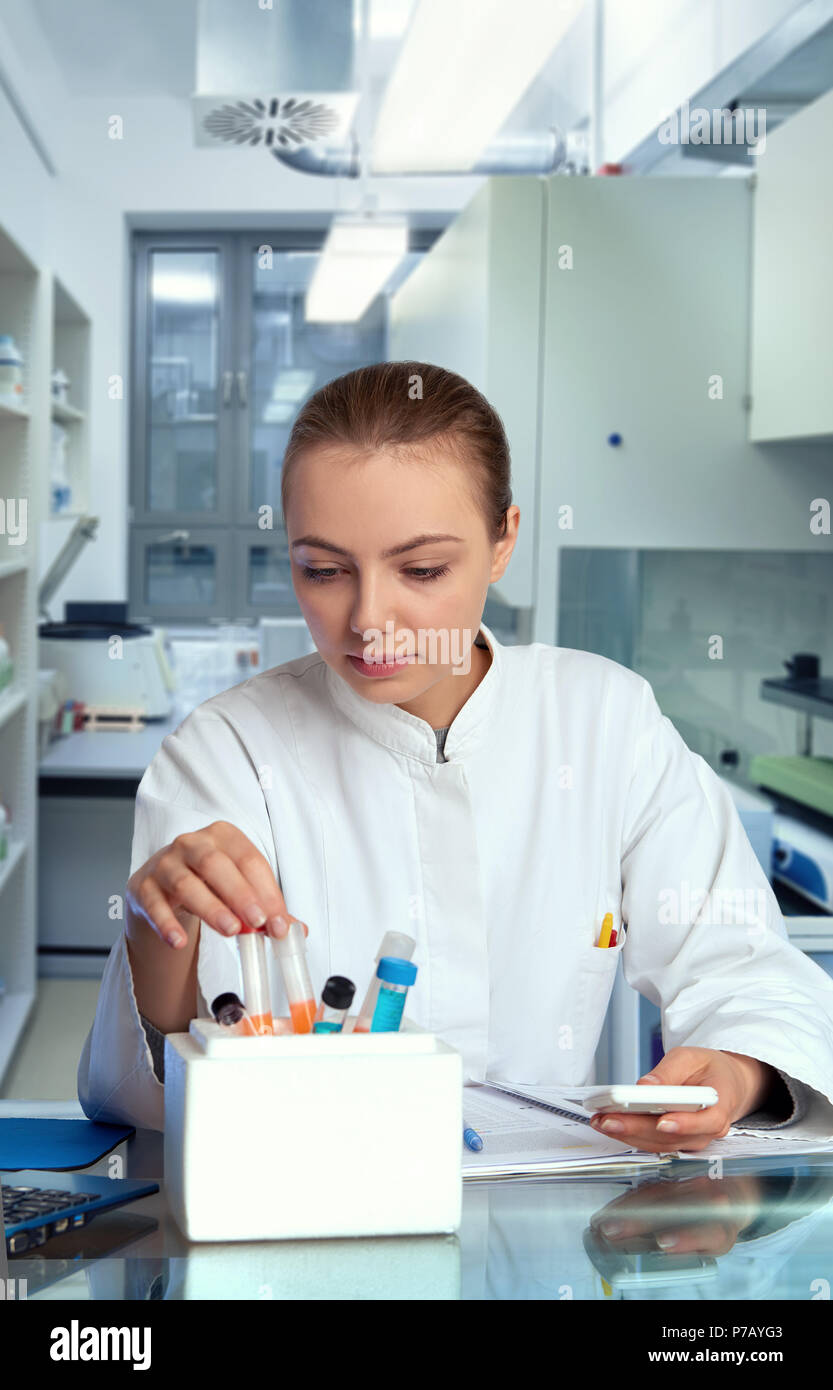 Junge weibliche Tech oder Wissenschaftler wählt ein Probenröhrchen aus Eis, Weißer ihre Timer Stockfoto