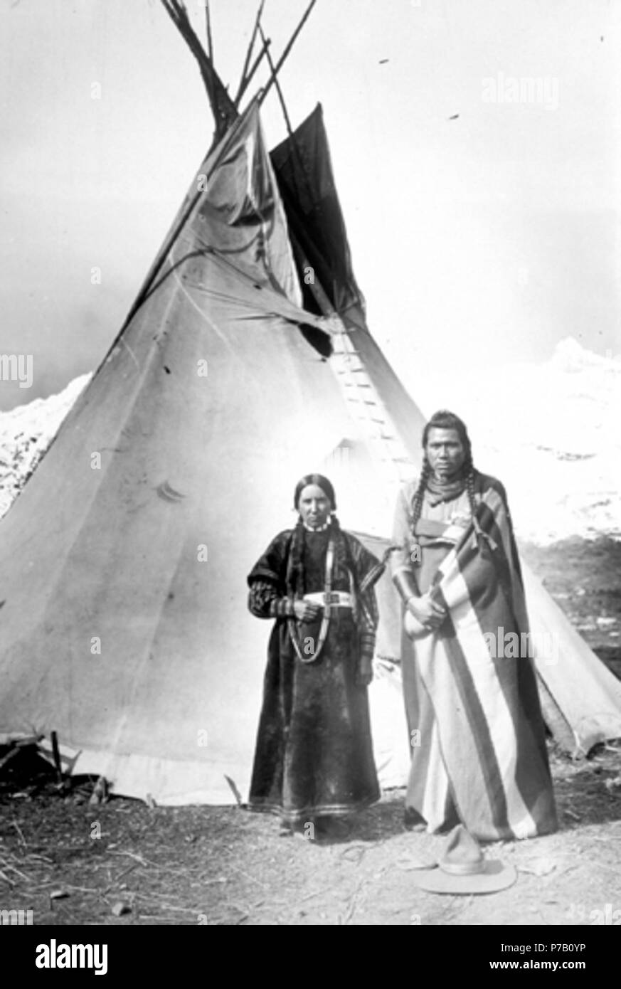 Englisch: Nez Perce Mann und Frau posieren vor Tipi, mit Berg hinter Ihnen. Frau in voller Länge Kleid über Bluse, mit lange Halskette & Perlen Gürtel steht neben Mann mit Decke über der Schulter und um die Hüfte. Plain tepee hinter Ihnen steht, und dahinter ist, schneebedeckte Gipfel. 59 Nez - Perce - Paar - teepee-1900 Stockfoto Englisch: Nez Perce Mann und Frau posieren vor Tipi, mit Berg hinter Ihnen. Frau in voller Länge Kleid über Bluse, mit lange Halskette & Perlen Gürtel steht neben Mann mit Decke über der Schulter und um die Hüfte. Plain tepee hinter Ihnen steht, und dahinter ist, schneebedeckte Gipfel. 59 Nez - Perce - Paar - teepee-1900 Stockfoto