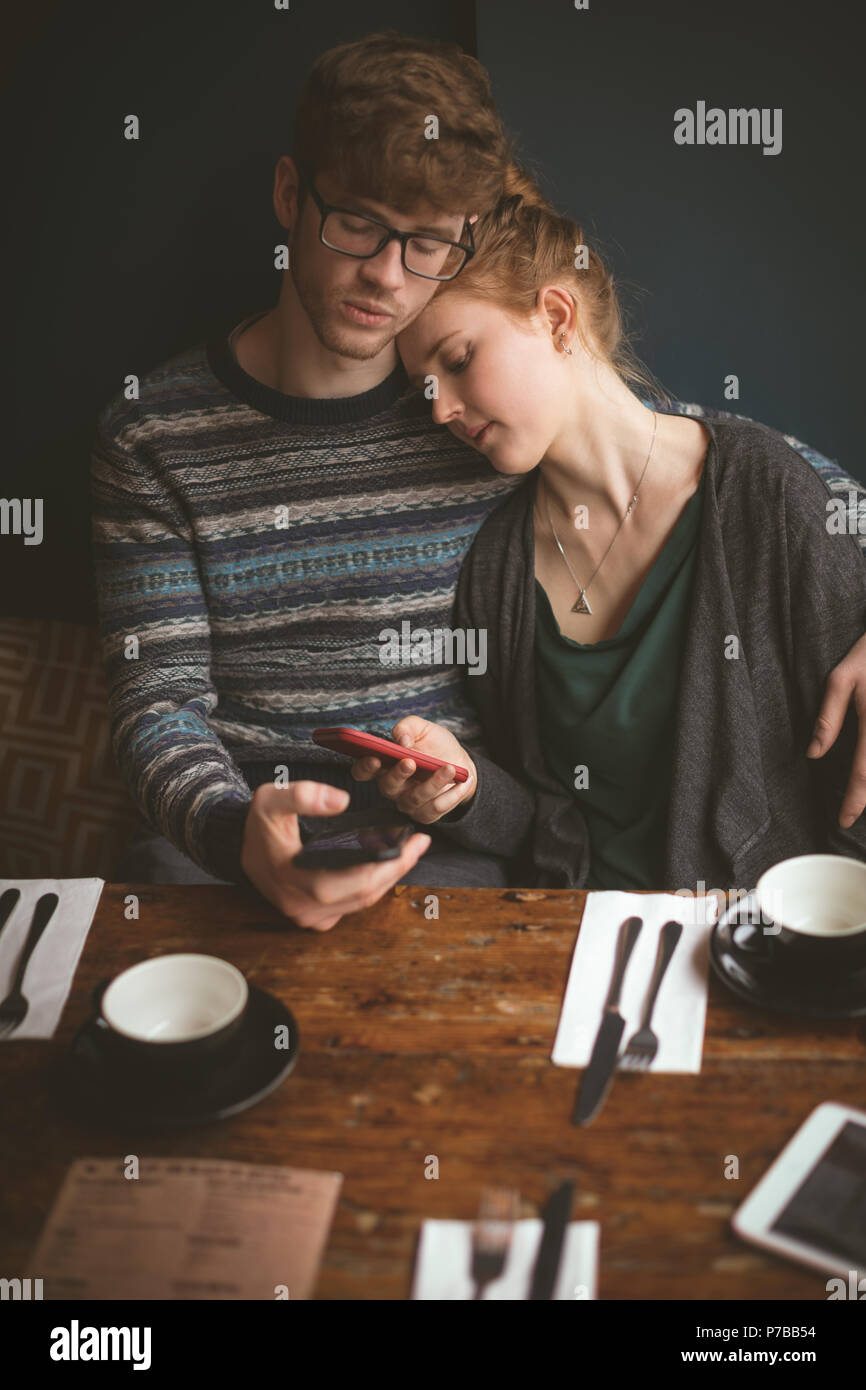 Paar umarmen und die Nutzung von Mobiltelefonen im Cafe Stockfoto