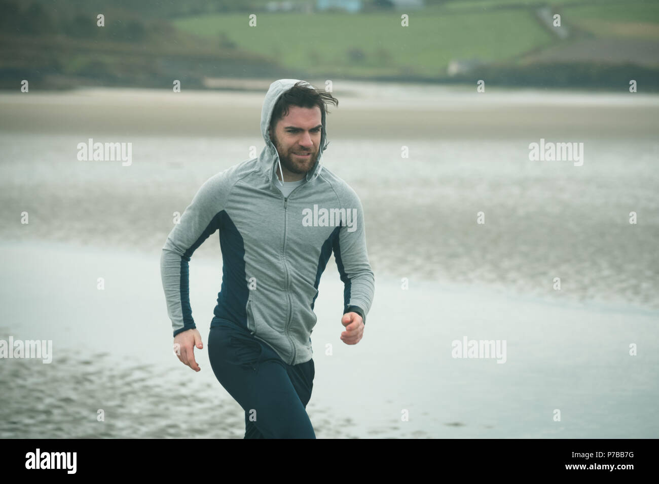 Mann in hoodie Jogging am Strand. Stockfoto