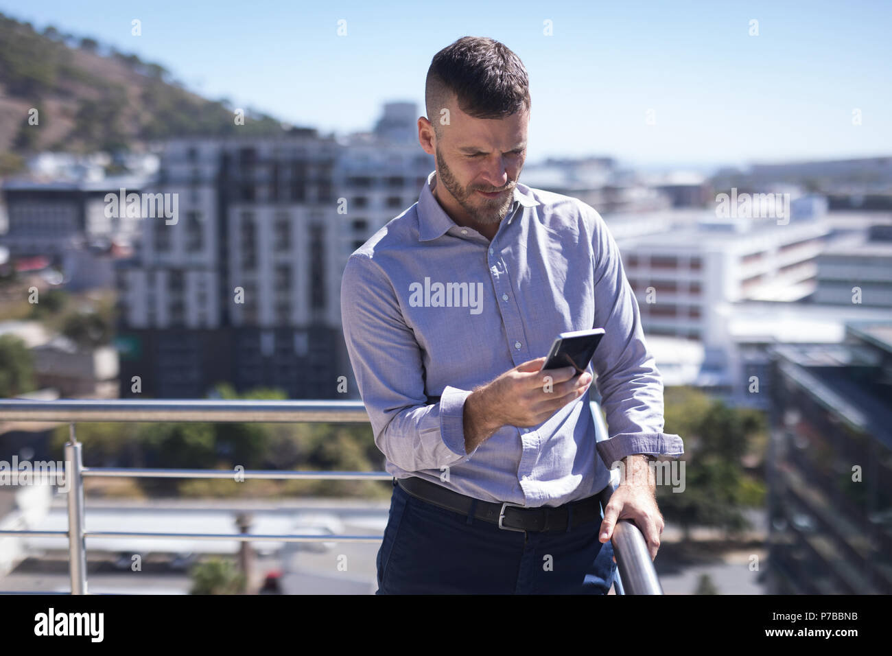 Unternehmer lehnen auf Geländer bei der Verwendung von Mobile phone Stockfoto