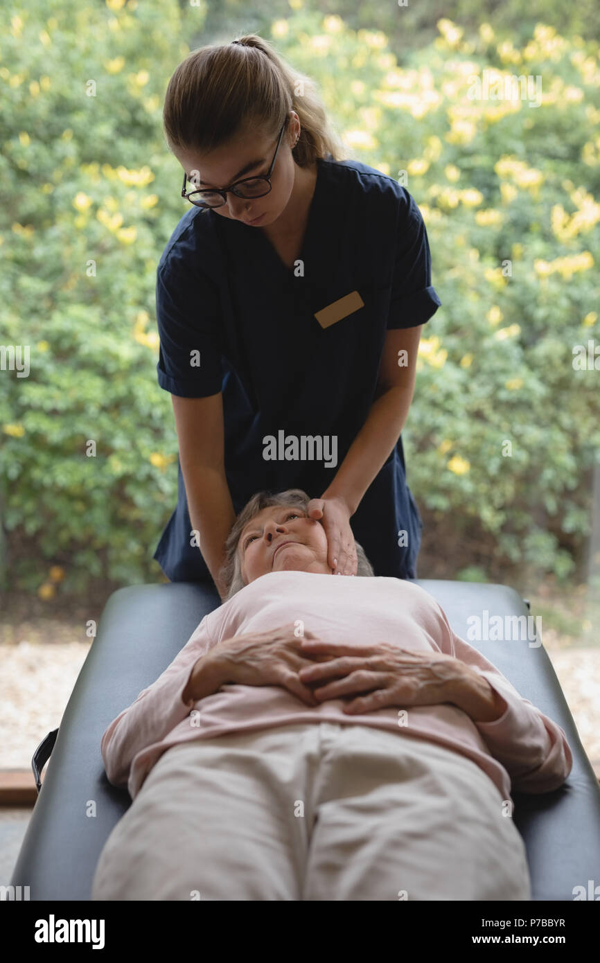 Physiotherapeuten mit einer Kopfmassage zu den älteren Frau Stockfoto