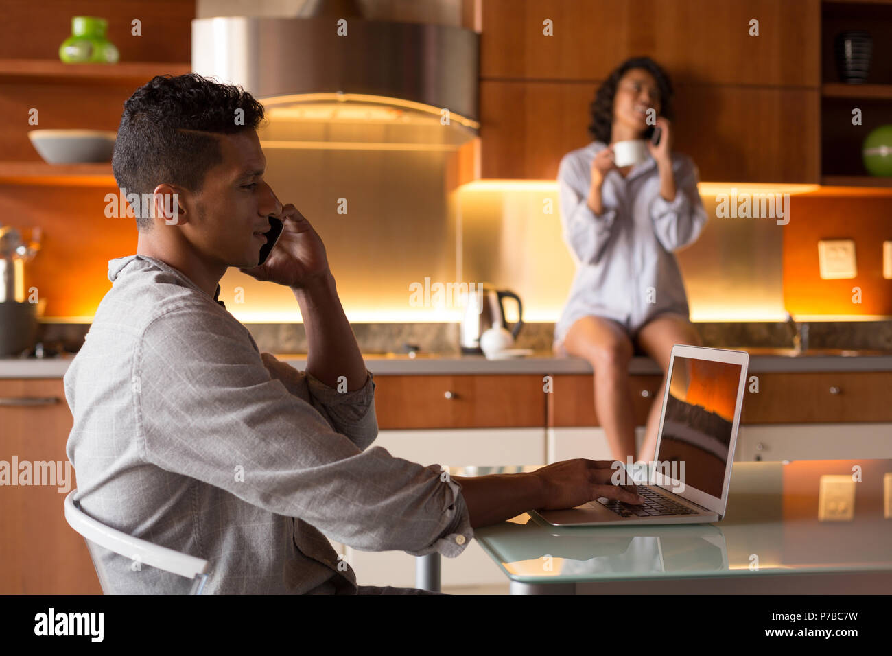 Mann, telefonieren mit Handy während mit Laptop in Küche Stockfoto