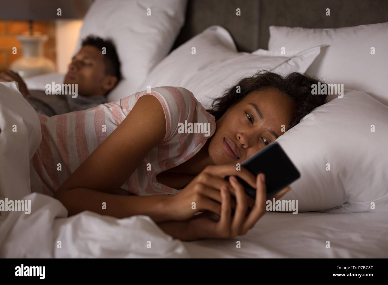 Paar mit Handy im Schlafzimmer Stockfoto