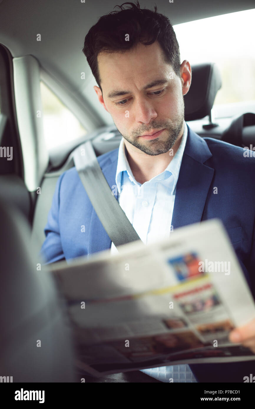 Geschäftsmann lesen Zeitung in einem Auto Stockfoto