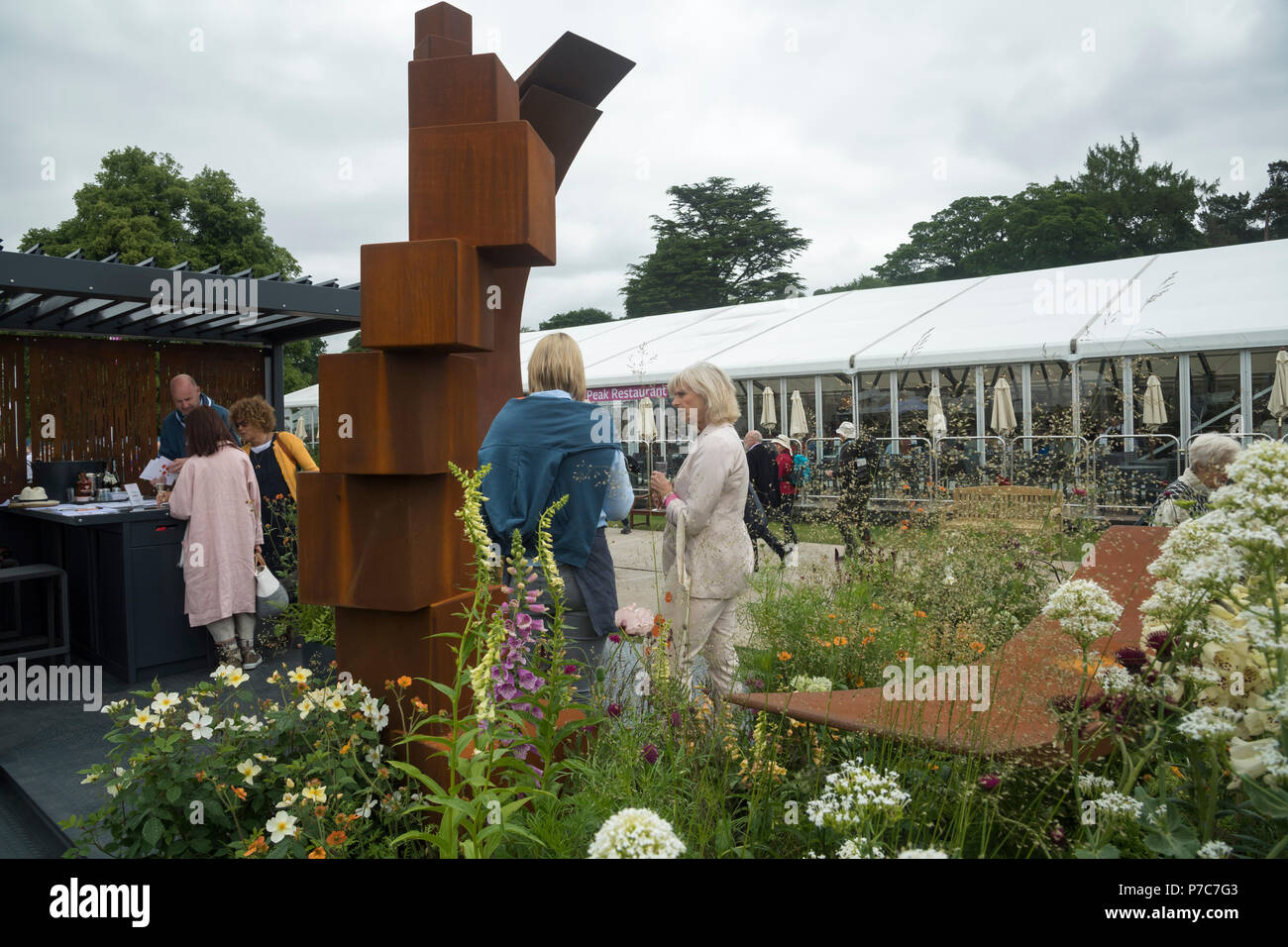 Leute stehen, Reden durch Anzeige der großen ursprünglichen Garten metall Skulpturen auf den Handel stand-RHS Chatsworth Flower Show, Derbyshire, England, Großbritannien Stockfoto