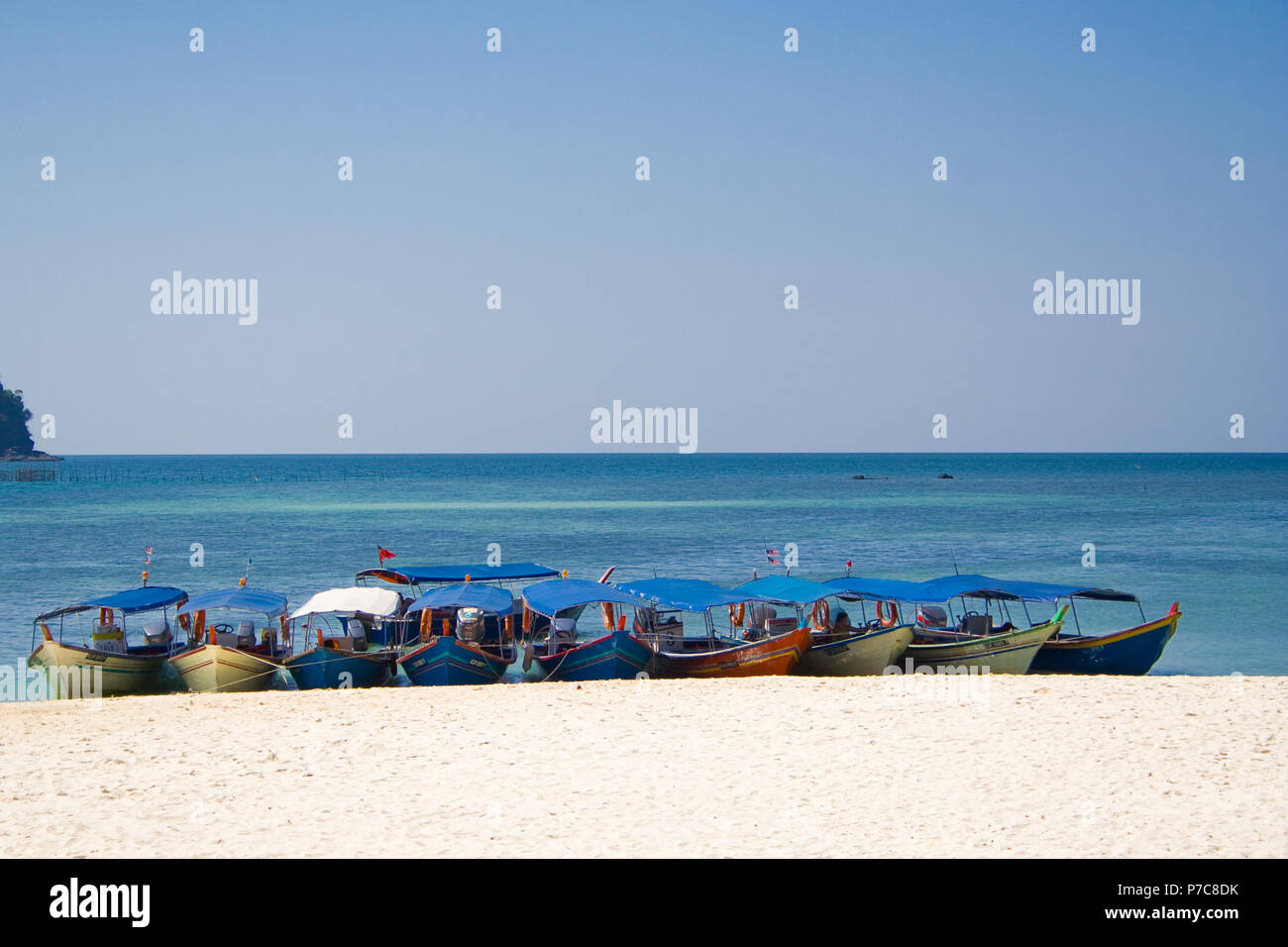 Mehrere überdachte Motorboote, verantwortlich für die Touristen, die nebeneinander vertäut am weißen Sandstrand von Pulau Beras Basah, eine Insel... Stockfoto