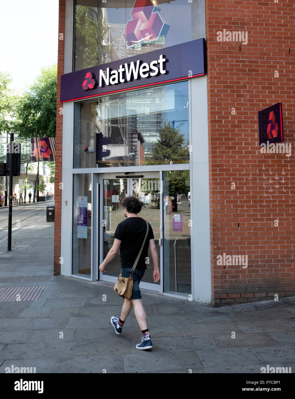 Ein junger Mann übergibt die ausserhalb eines modernen Zweig der NatWest Bank in Manchester, Großbritannien Stockfoto