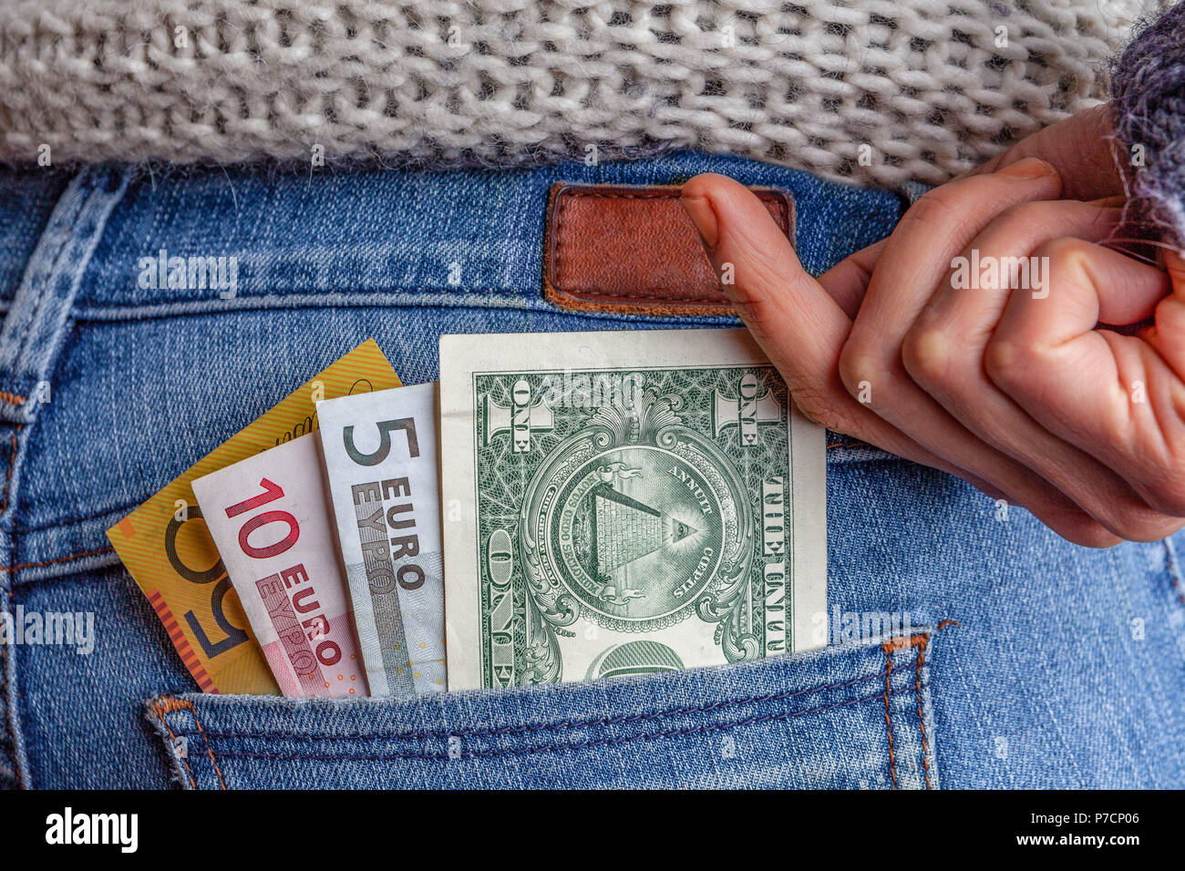Internet Business, Gewinne, Reisen und Finanzen Konzept - USD, AUD, EUR und in der Tasche auf der Rückseite der blauen Jeans mit weiblichen Hand erreichen für das Geld Stockfoto