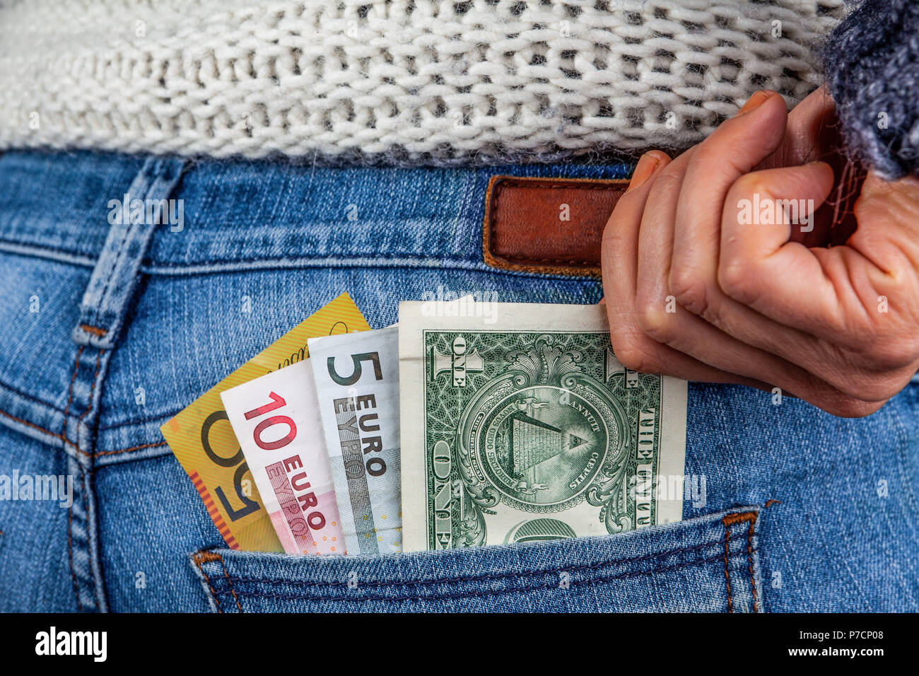 On-line-Geschäft, Gewinne, Reisen und Finanzen Konzept - USD, AUD, EUR und in der Tasche auf der Rückseite der blauen Jeans mit weiblichen Hand erreichen für das Geld Stockfoto