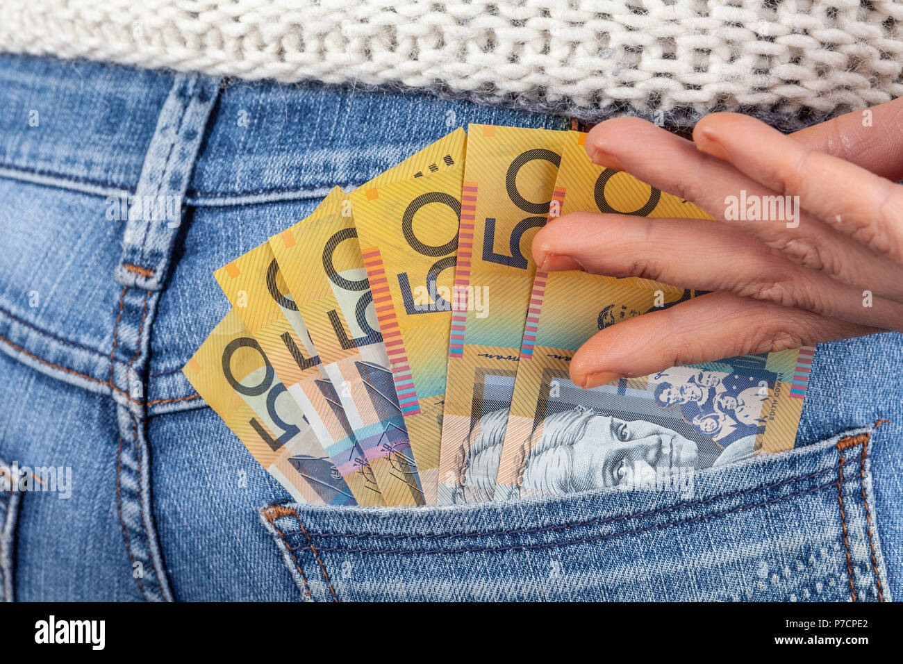Weibliche Hand erreichen für 50 australische Dollar Scheine in ihre Jeans Gesäßtasche Stockfoto