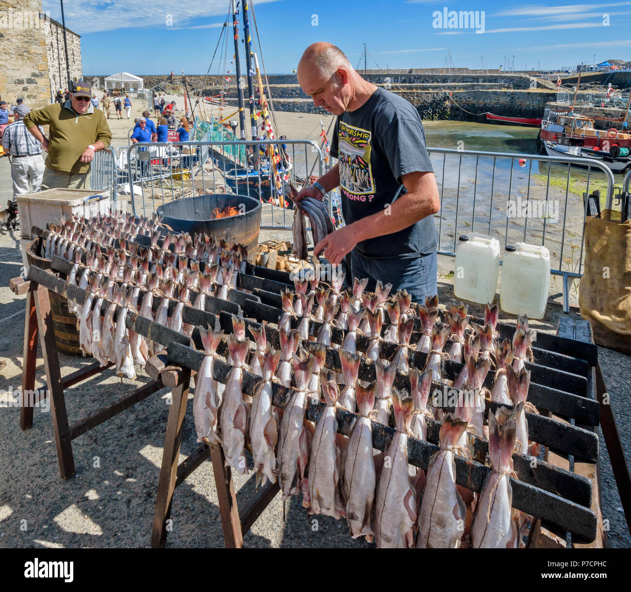 PORTSOY FESTIVAL ABERDEENSHIRE SCHOTTLAND Arbroath Smokies Schellfisch Fisch zubereitet auf Regalen VOR DEM RAUCHEN UND EIN FEUER MIT FLAMMEN IM FASS Stockfoto