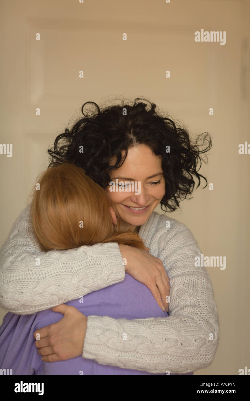 Mutter und Tochter einander umarmen im Wohnzimmer Stockfoto