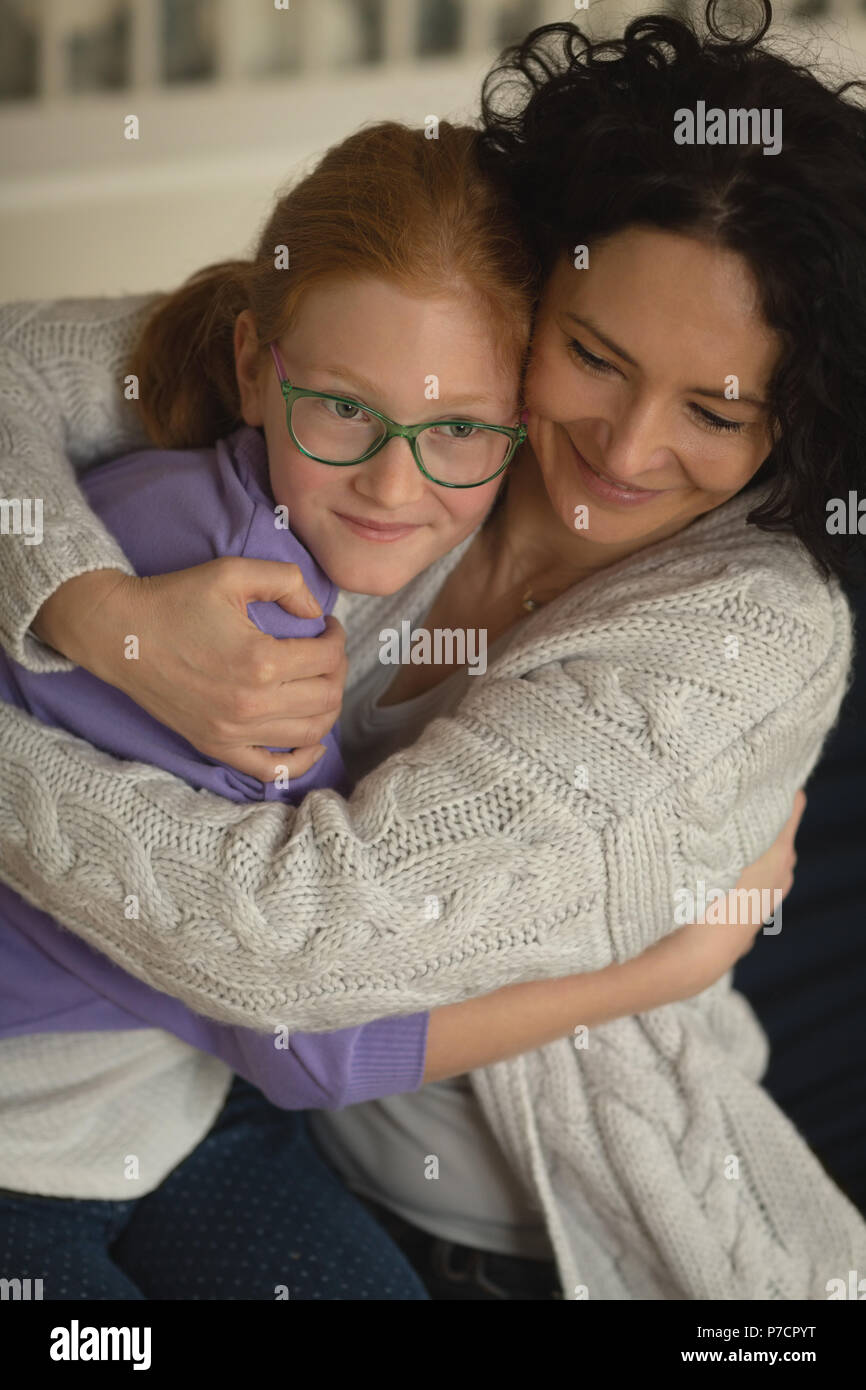 Mutter und Tochter einander umarmen im Wohnzimmer Stockfoto