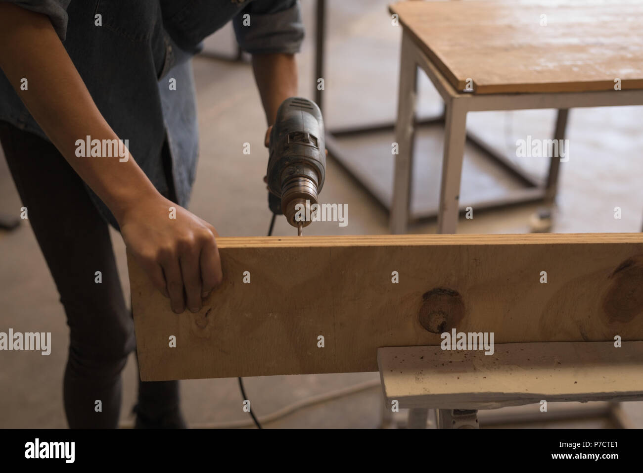 Weibliche Schweißer mit Bohrmaschine in der Werkstatt Stockfoto