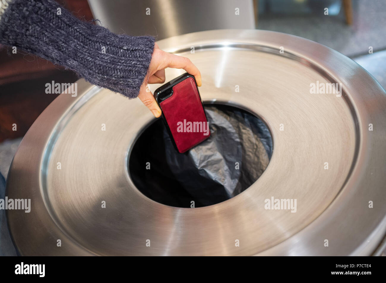 Weibliche Hand wegzuwerfen Mobiltelefon in Mülleimer Stockfoto
